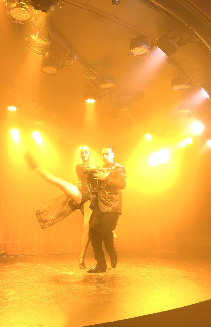 Tango dancers under red stage light
