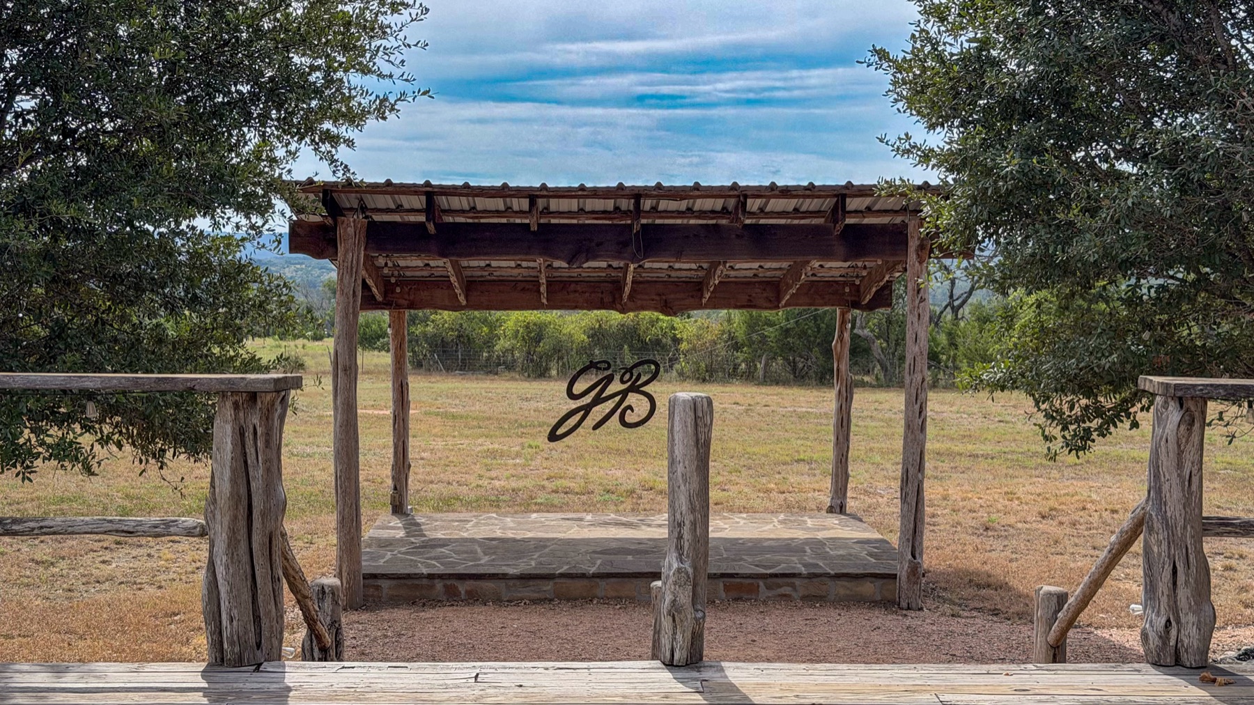 The GB monogram arbor at Garrison Brothers with Hill Country behind it