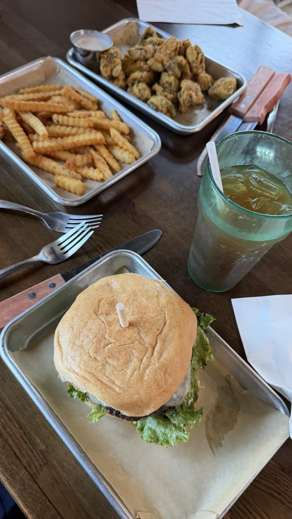 The Peachy Jalapeño burger on a metal tray with crinkle fries and fried okra behind it