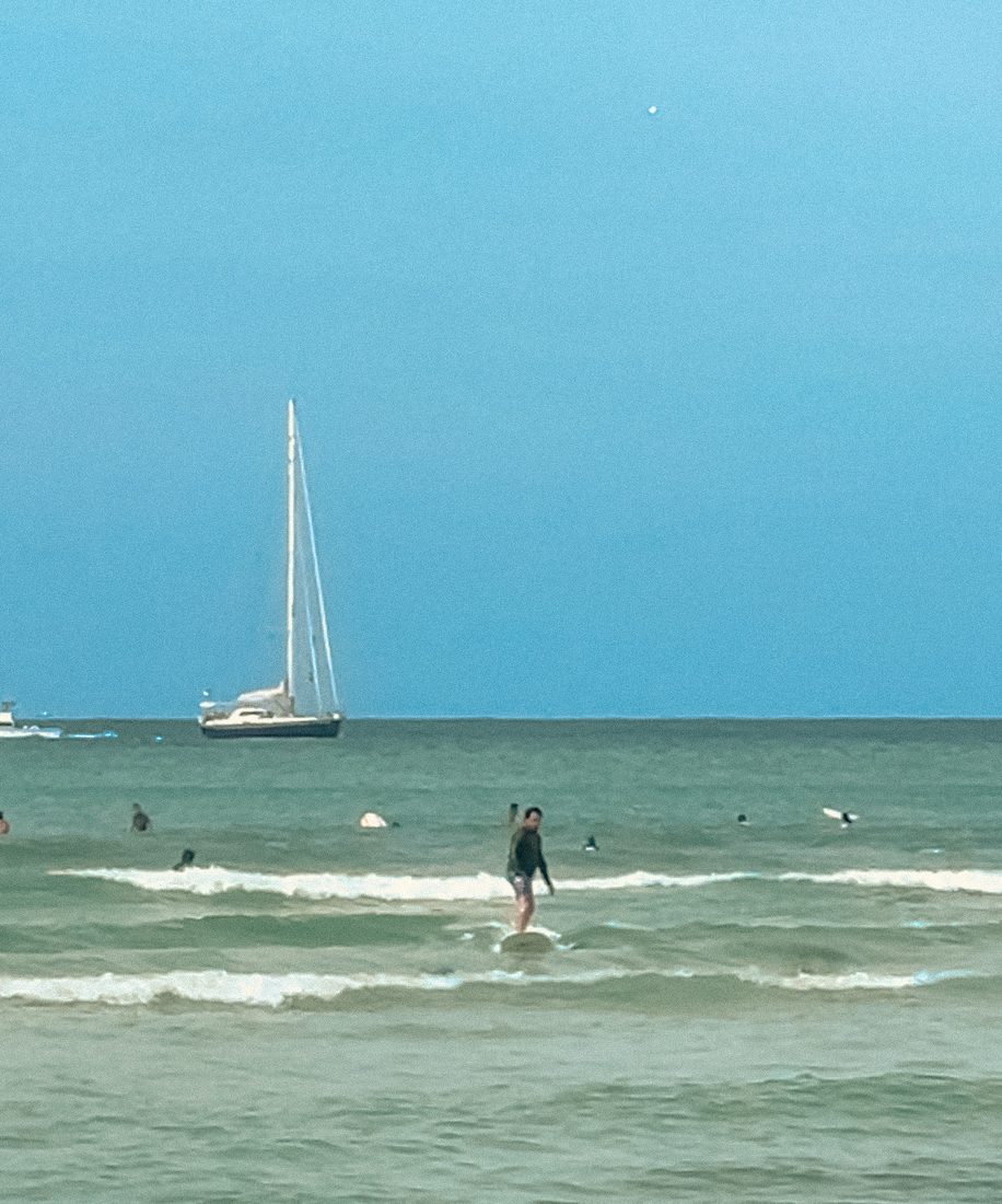 Turquoise water with a sailboat and a paddleboarder