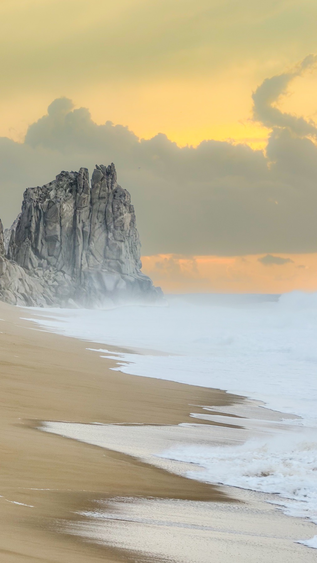 Land's End rock formation in heavy surf at sunset