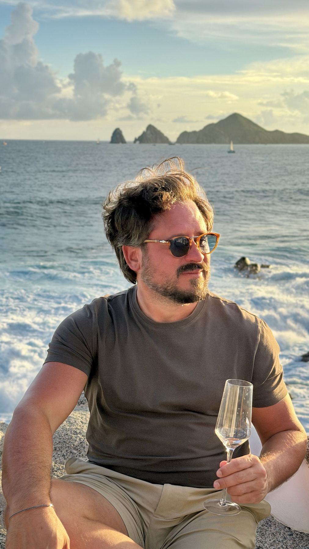Matt on the rocks with a glass of champagne, Land's End behind