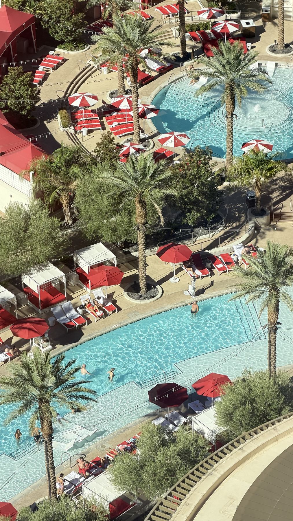 The resort pool complex seen from high above, red umbrellas and palms
