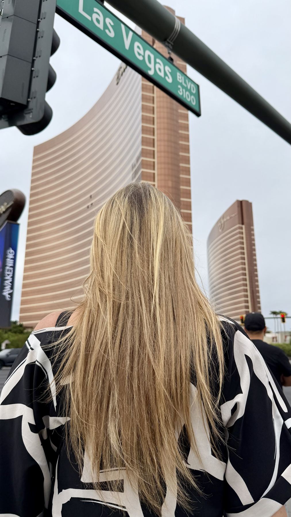 Amber looking up at the Wynn and Encore towers beneath a Las Vegas Blvd street sign